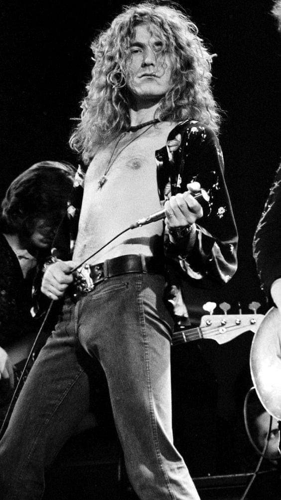 an old black and white photo of a man with long hair playing guitar on stage