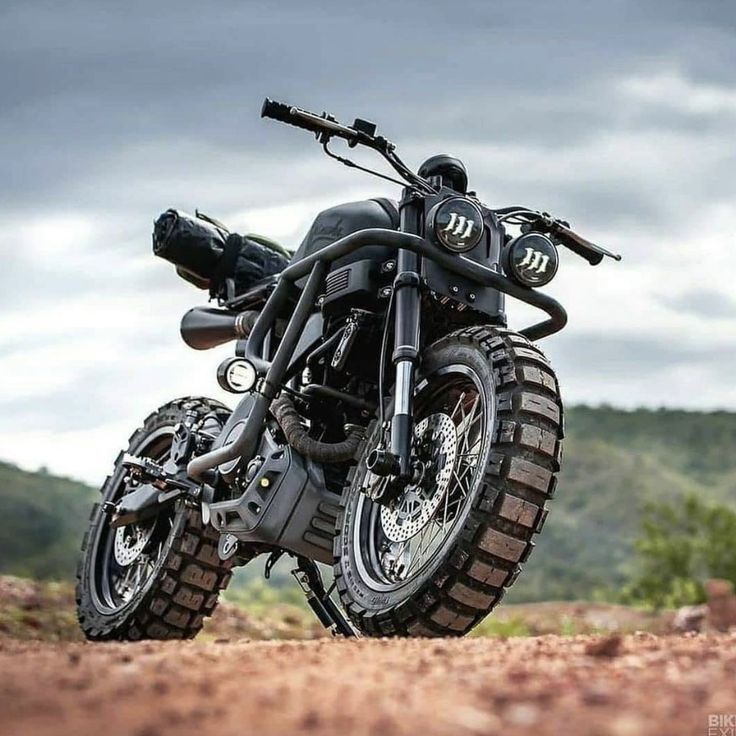 a black motorcycle parked on top of a dirt field