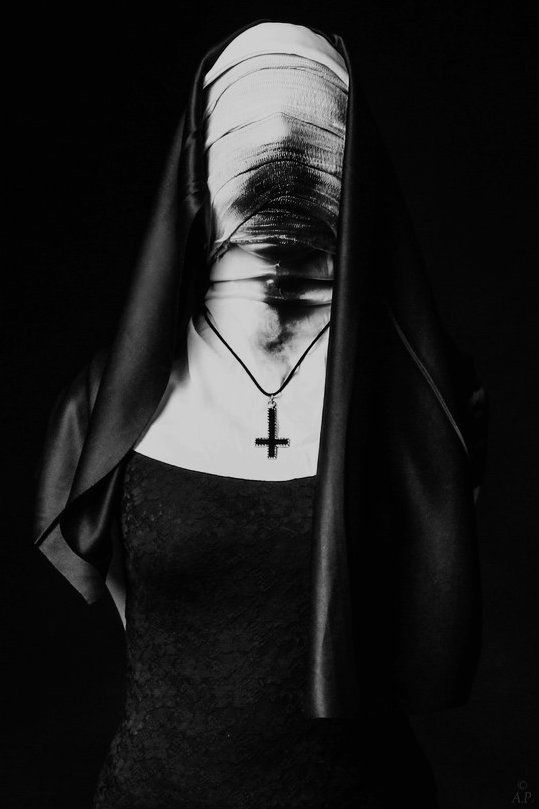 a black and white photo of a woman with a cross on her neck wearing a veil