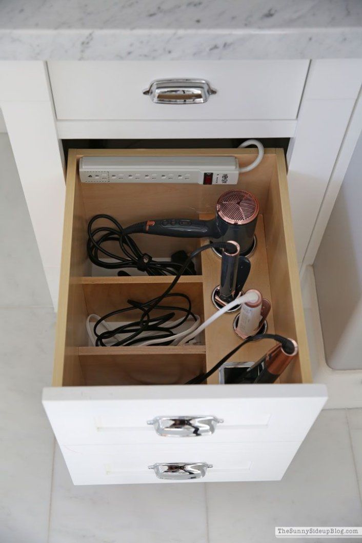 an open drawer with hairdryers and other items in it on the counter top