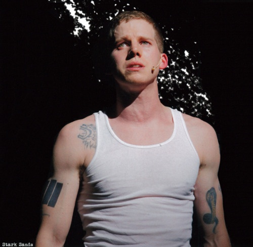 a man with tattoos standing in the dark