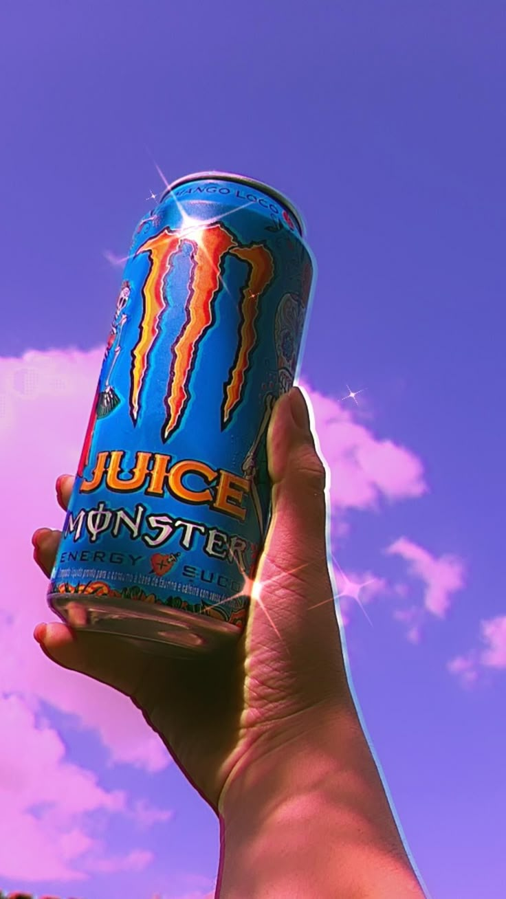 a person holding up a can of juice in front of a blue sky with clouds