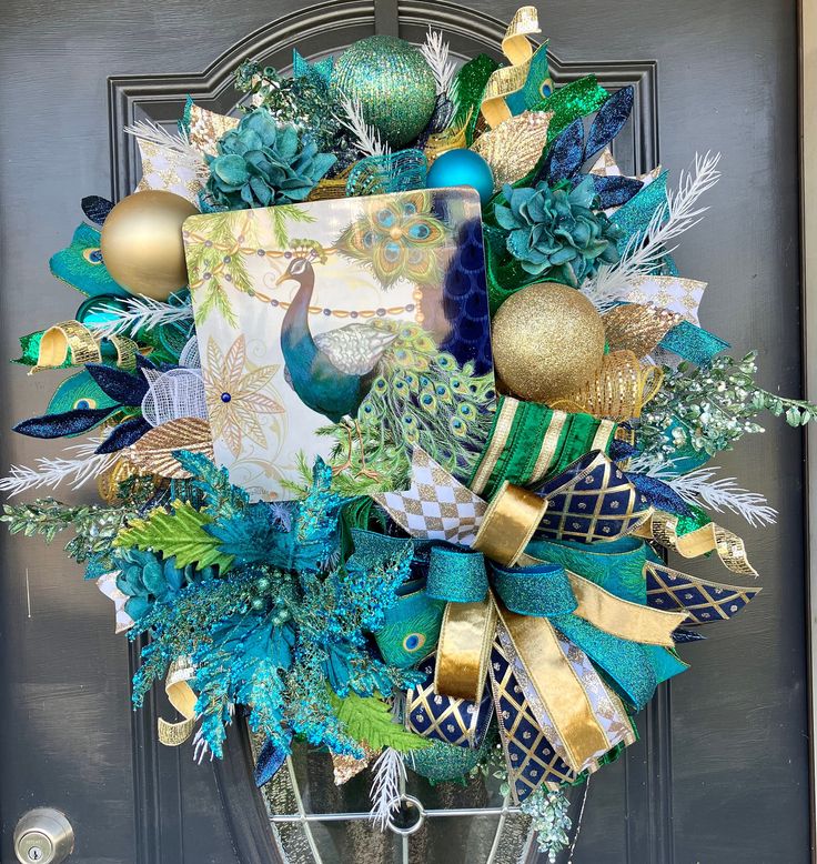 a christmas wreath with green, gold and blue decorations hanging on a front door handle