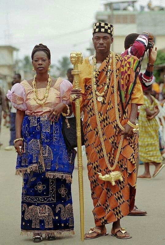 two people standing next to each other in front of a crowd wearing african clothing and headdress