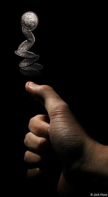 a person's hand holding an object in front of a black background with the light reflecting on it