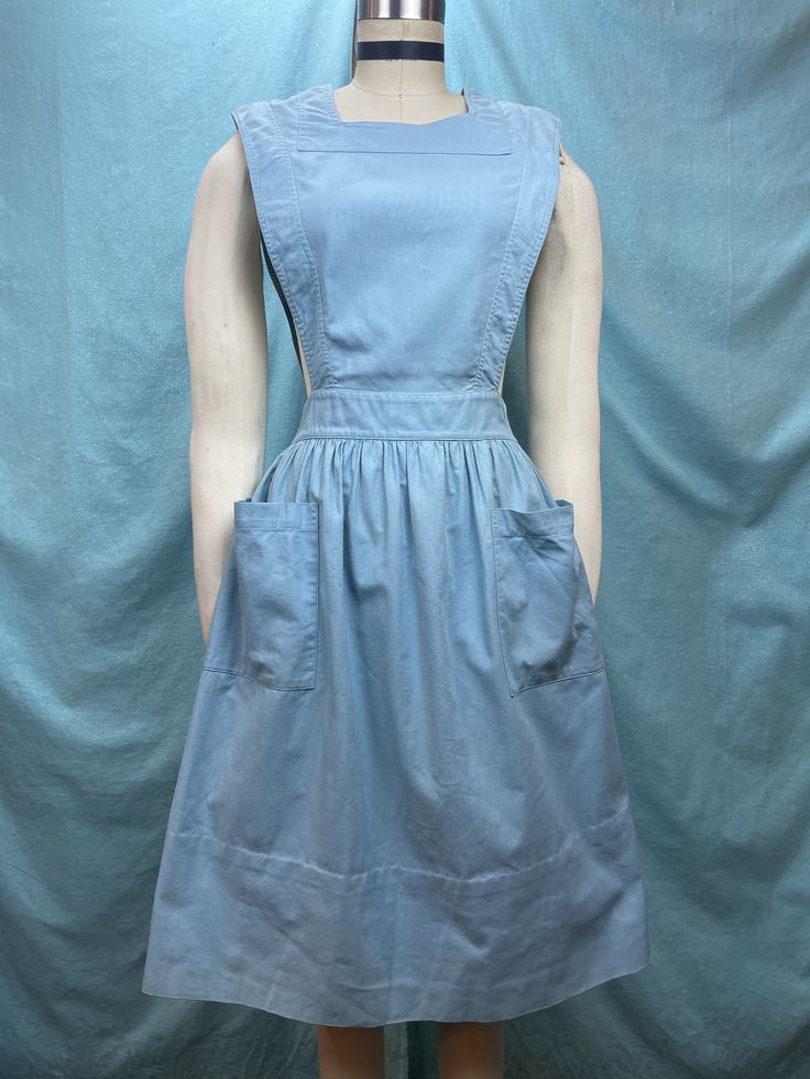 "1940s W:25 Angelica vintage pinafore sleeveless apron uniform dress pockets canvas cotton linen sanforized blue aqua button up square neck fit flare  Great 40s uniform dress from Angelica. Classic uniform pinafore silhouette of sleeveless bib with gathered flare skirt. Reinforced armholes, neckline and waistline. Button down with white buttons in the back. Two slanted oversized front pockets. Sanforized canvas cotton linen fabric in sweet shade of vintage blue aqua contrasted. Photographed on f Vintage Square Neck Dress, Cotton Workwear Apron With Pockets, Sleeveless Cotton Apron With Pockets, Blue Cotton Pinafore Dress With Pockets, Cotton Apron With Pockets, Vintage Cotton Pinafore Dress With Pockets, Fitted Cotton Pinafore Dress For Work, Solid Color Vintage Cotton Dress, Cottagecore Cotton Dresses With Pockets