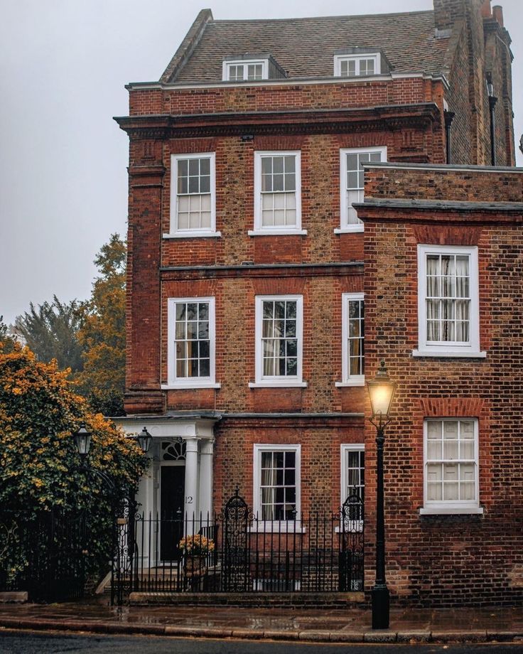 an old brick building with white windows and iron fenced in area next to it