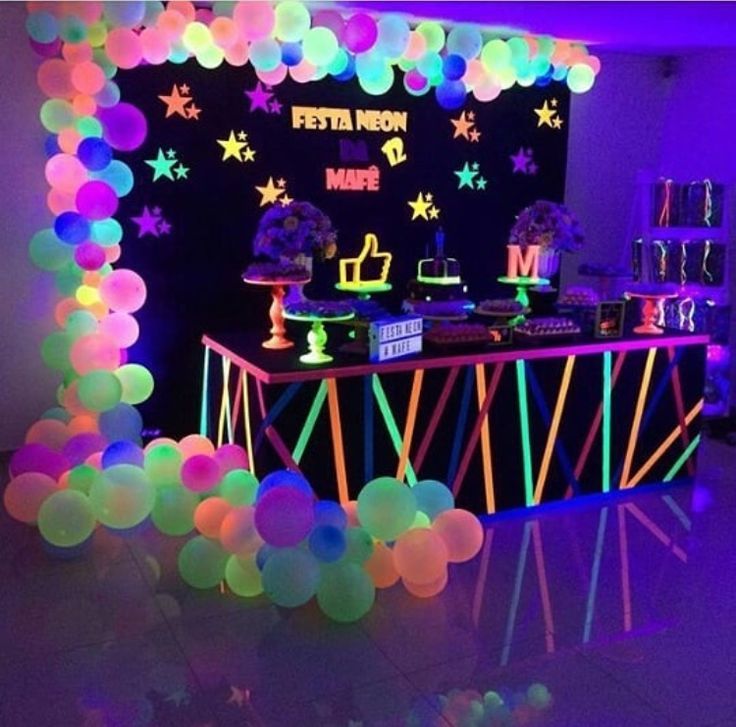 a party with neon lights and balloons on the walls is ready for guests to eat