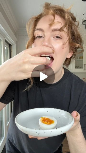 a woman holding a bowl with an egg in it and making a funny face at the camera