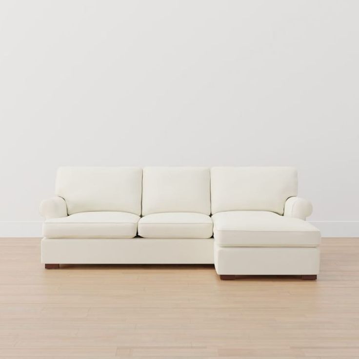 a white couch sitting on top of a hard wood floor next to a white wall