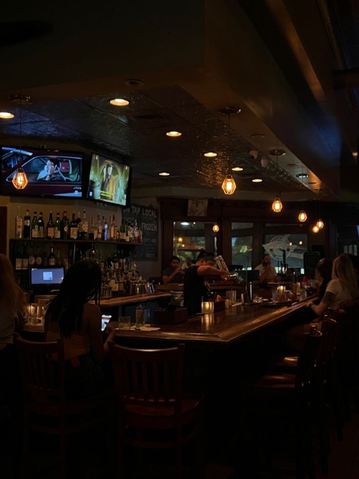 people are sitting at the bar watching tvs