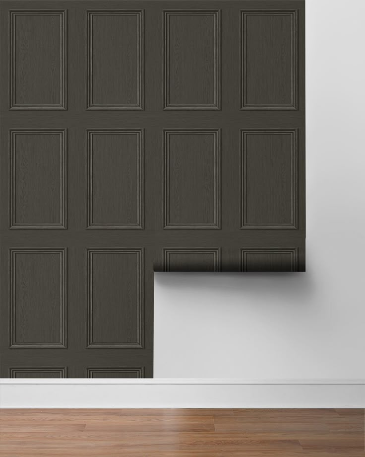 an empty room with a black door and wooden flooring on the wall next to it