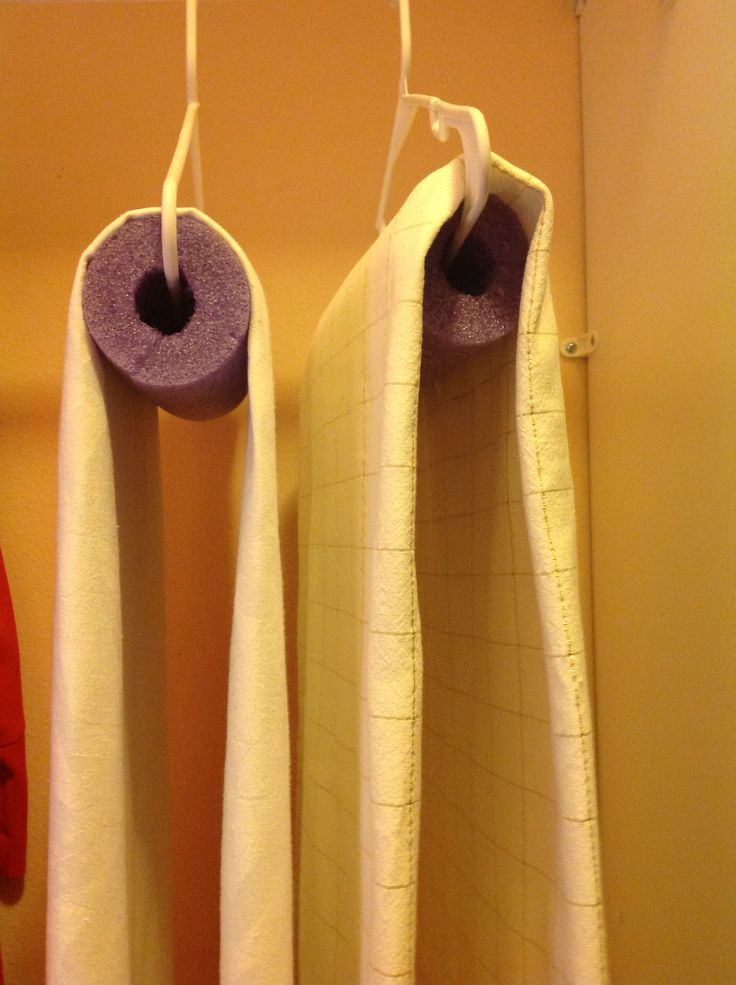 two white towels hanging from hooks in a bathroom