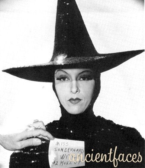 a woman wearing a witches hat holding a sign