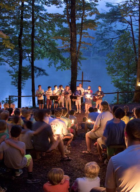 a group of people sitting on top of a forest next to a body of water