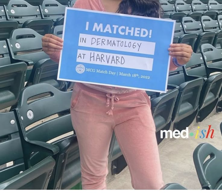 a woman holding up a sign that says i matched in dermatologisty at harvard