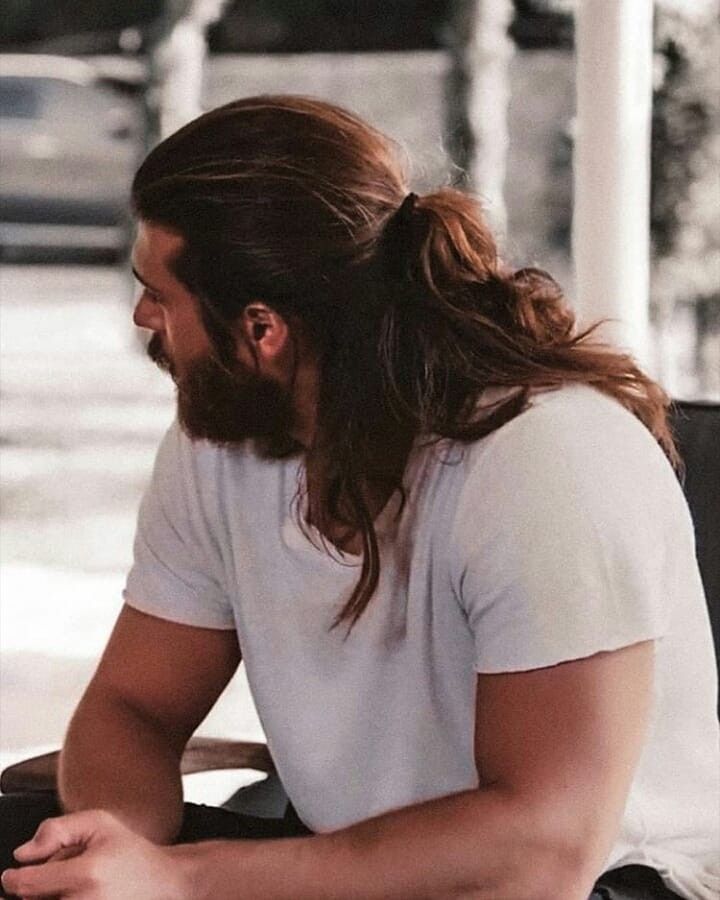 a man with long hair sitting on a bench