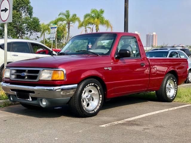 a red pick up truck parked in a parking lot next to other cars and trucks