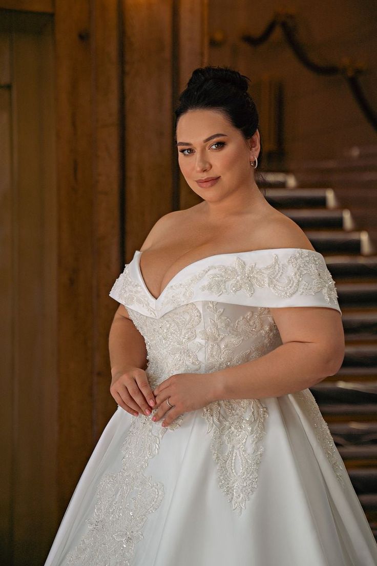 a woman in a white wedding dress posing for the camera with her hands on her hips