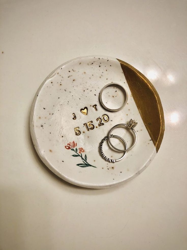 two wedding rings are placed on a plate with the word love spelled in gold lettering