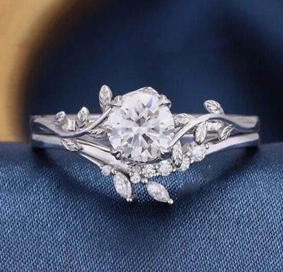 a white gold engagement ring with leaves on the band and a round diamond center stone