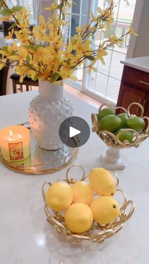 a table topped with bowls filled with lemons and limes next to a candle