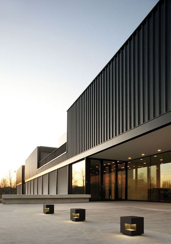 an empty courtyard in front of a building with black columns and lights on the ground