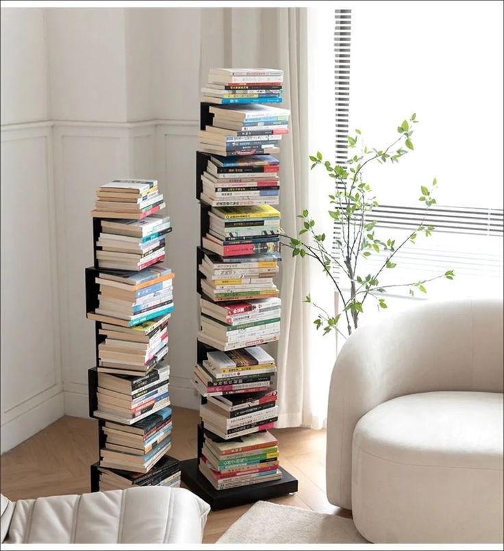 a tall stack of books sitting next to a white couch