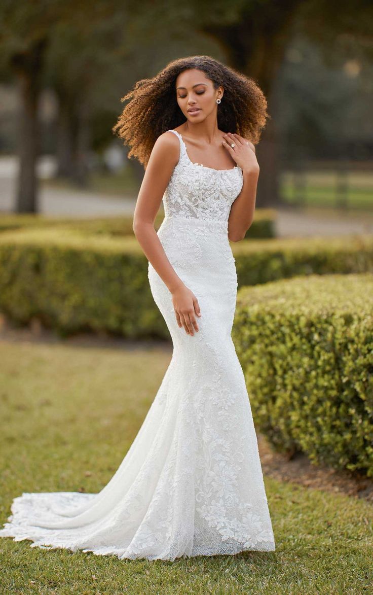 a woman in a white wedding dress standing on the grass with her hair blowing in the wind