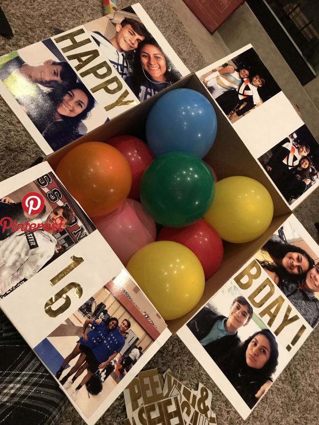 a box filled with balloons sitting on top of a carpeted floor next to pictures