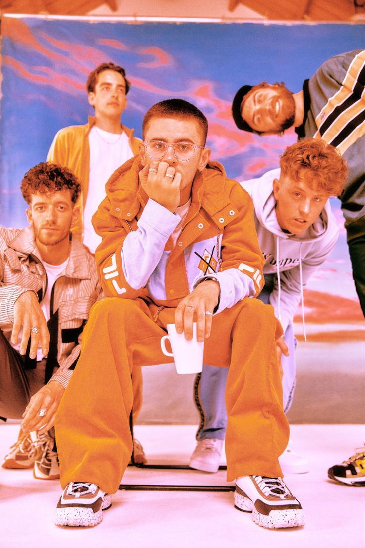 a group of young men sitting next to each other on top of a skateboard