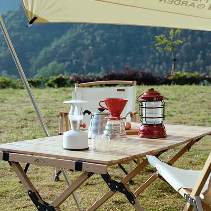 a table with two chairs and an umbrella on top of it in the middle of a field