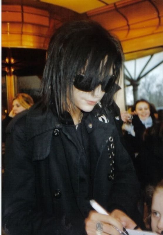 a woman with black hair and sunglasses writing on a piece of paper in front of other people