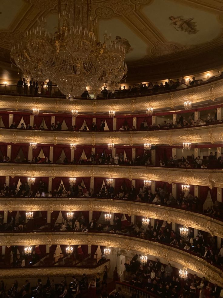 an auditorium filled with people and chandeliers