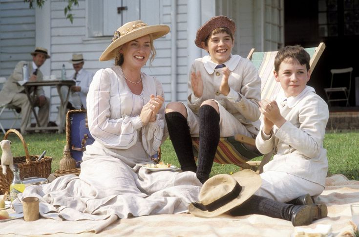 three people sitting on a blanket in front of a house