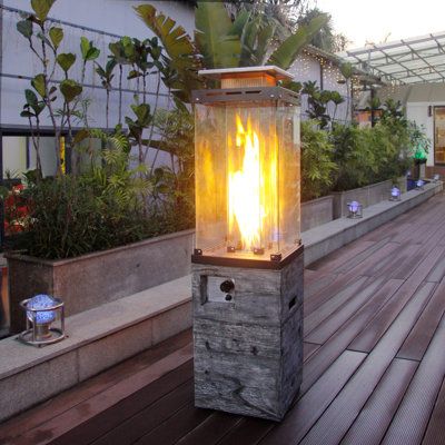 an outdoor fire pit on a deck with plants and potted trees in the background