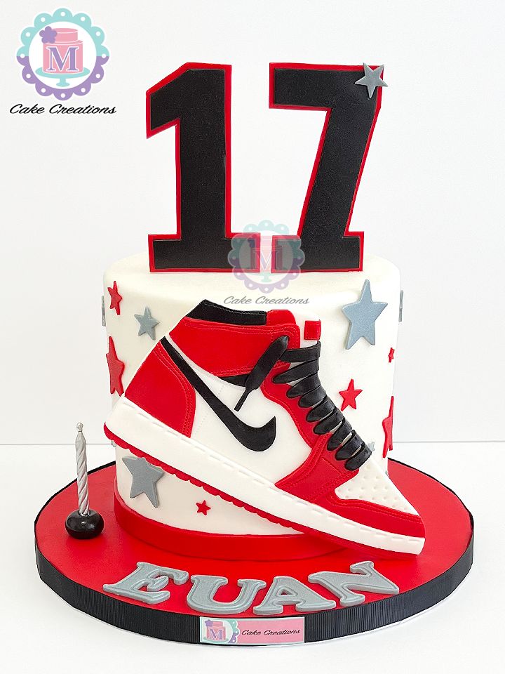 a red and white cake with a pair of sneakers on the top is decorated with silver stars