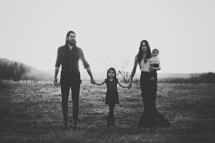 an adult and two children holding hands while standing in a field