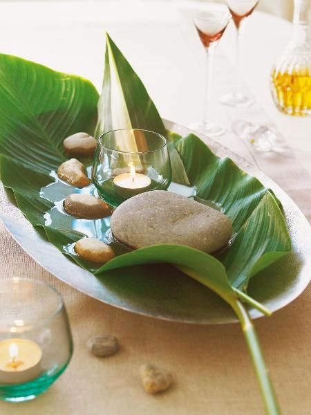 a plate with rocks and candles on it sitting on a table next to some wine glasses