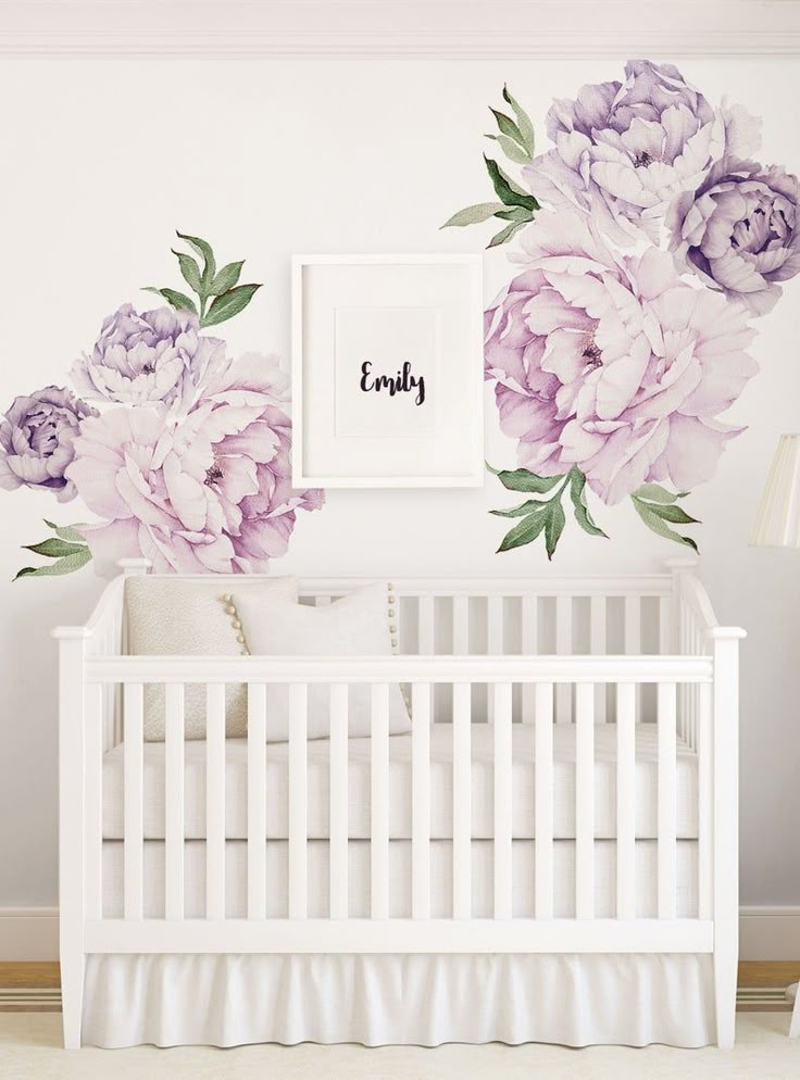 a white crib with purple flowers on the wall