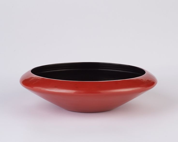 a red and black bowl sitting on top of a white table