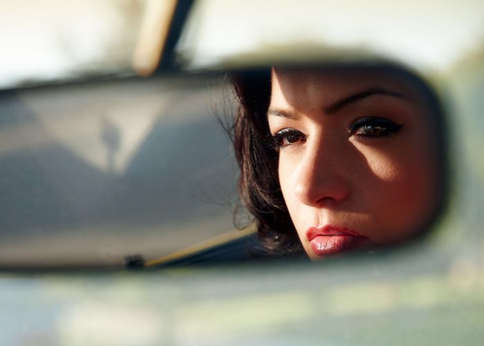 a woman looking out the side mirror of a car