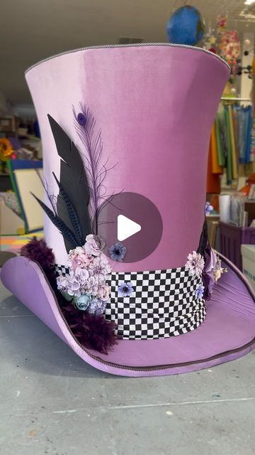 a purple top hat with black and white feathers on it's brimmed crown