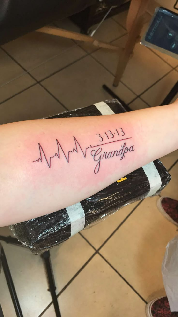 a woman's arm with a heartbeat and the words grandpa written on it in cursive writing