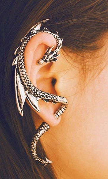 a close up of a person's ear with two snakes wrapped around it and one behind the ear