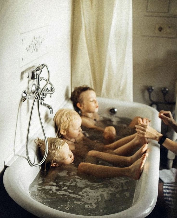 three children are sitting in the bathtub with their hands together