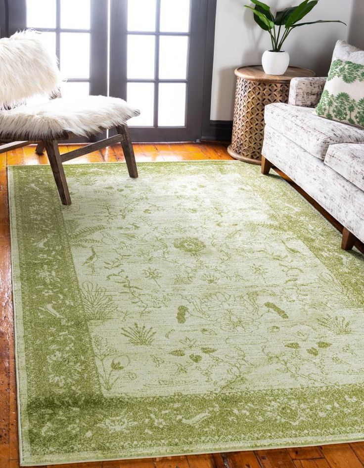 a living room filled with furniture and a green rug on top of a hard wood floor