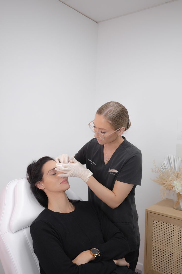 a woman getting her nails done by a professional maniist in a salon room with white walls