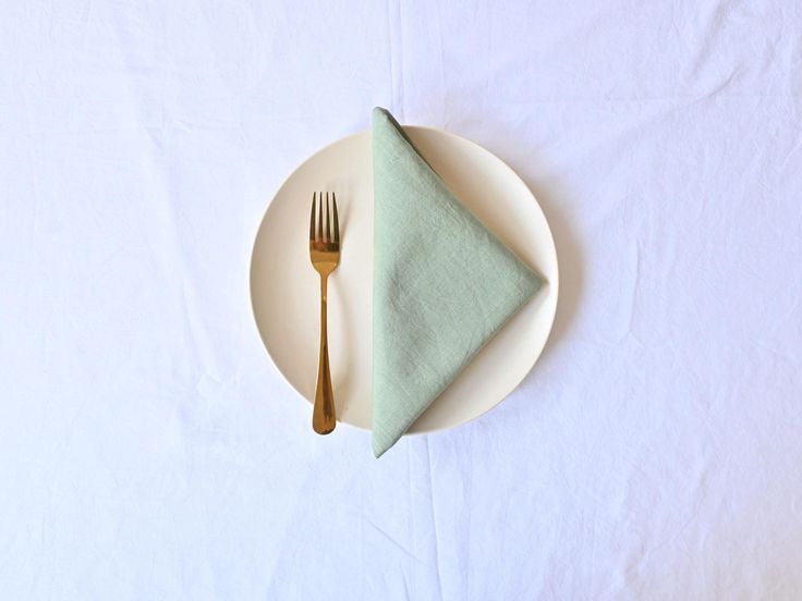 a white plate topped with a green napkin next to a fork