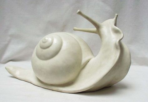 a white ceramic snail figurine on a white background